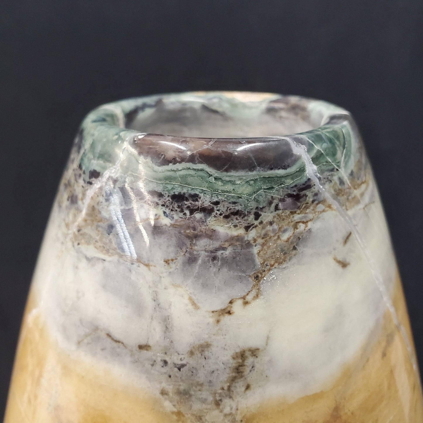 close up of green, brown, gray and white veins within a peacock marble vase