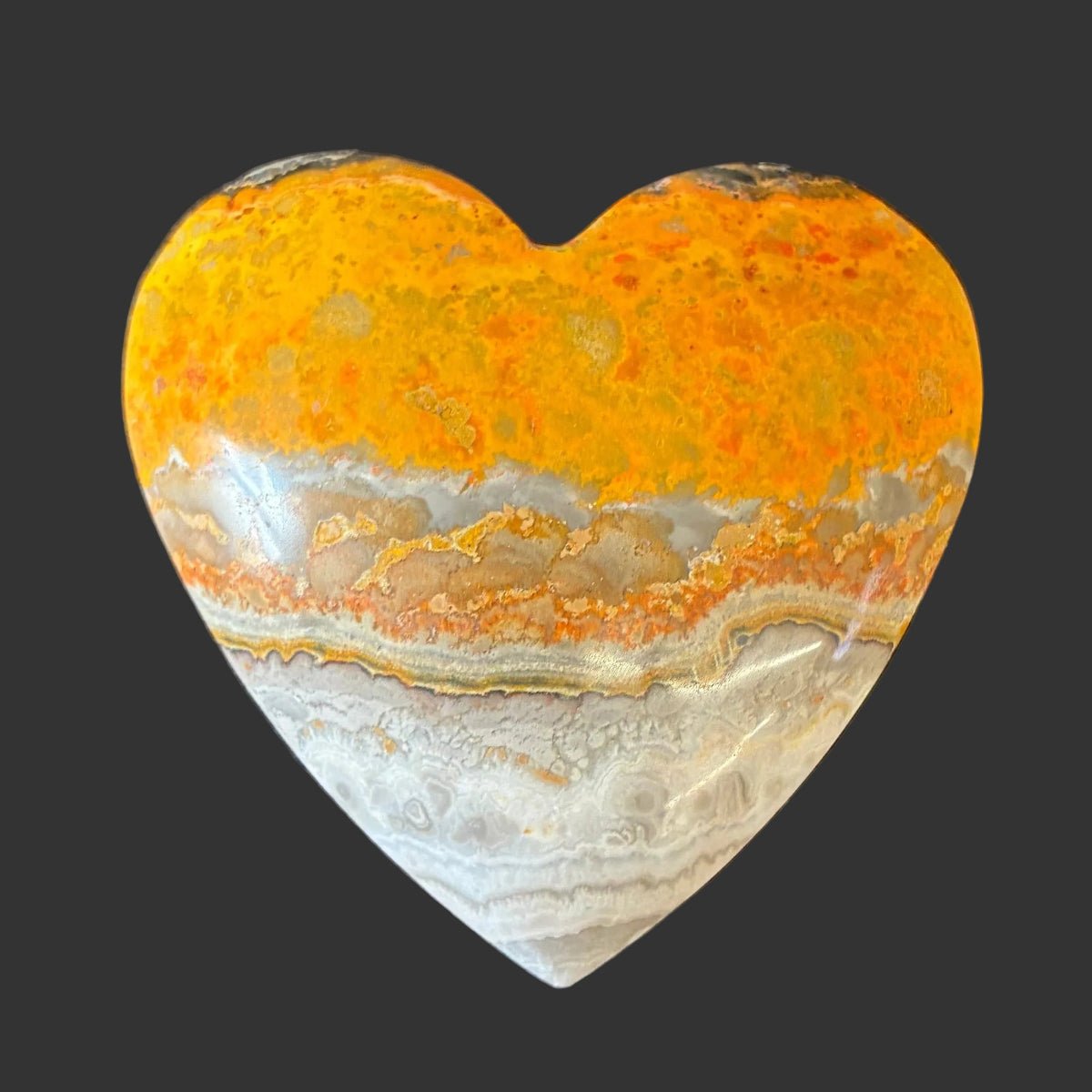 Back side of this bumblebee jasper heart, in front of a black background.