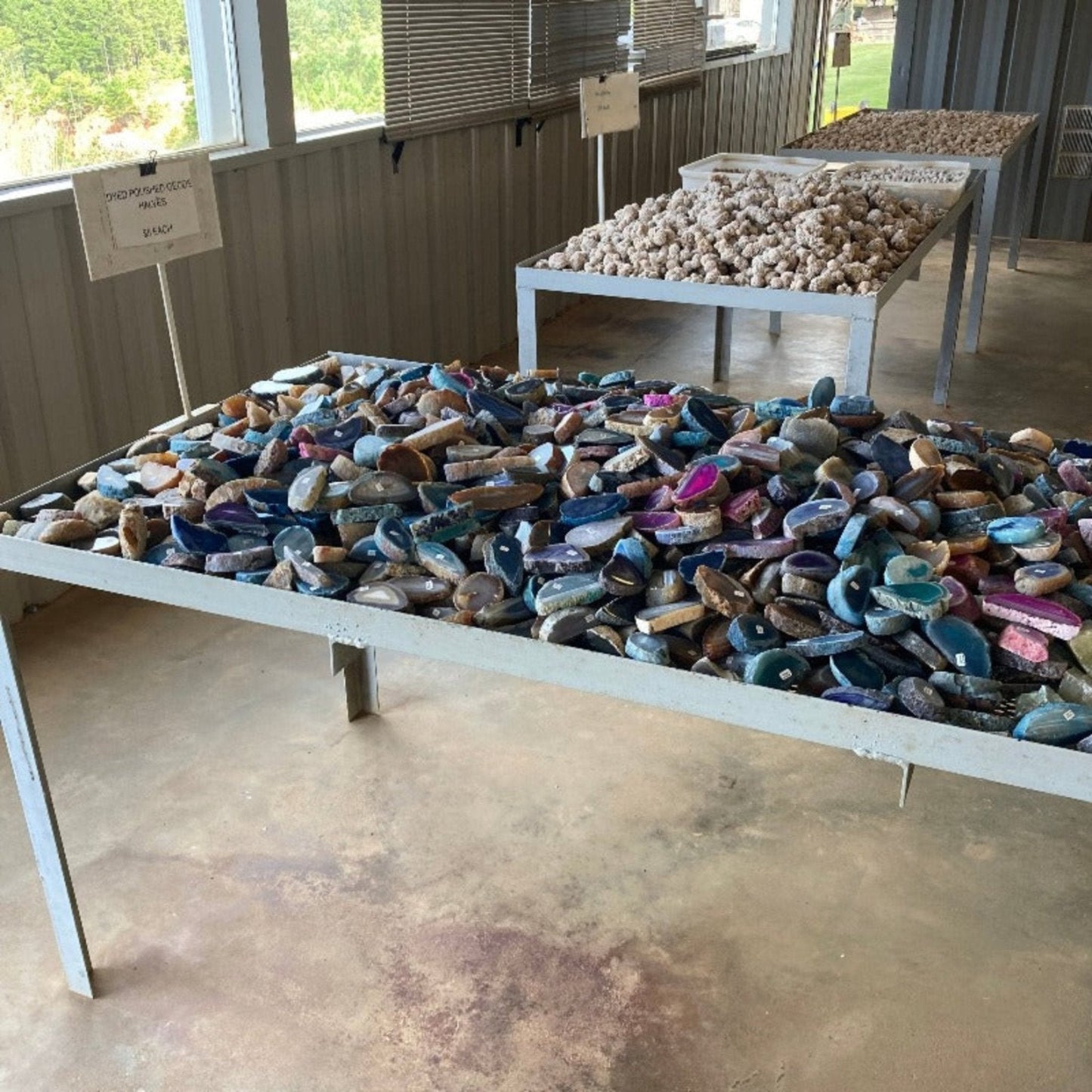 Table Of Colorful Dyed Geode Halves Polished with other stones in the background
