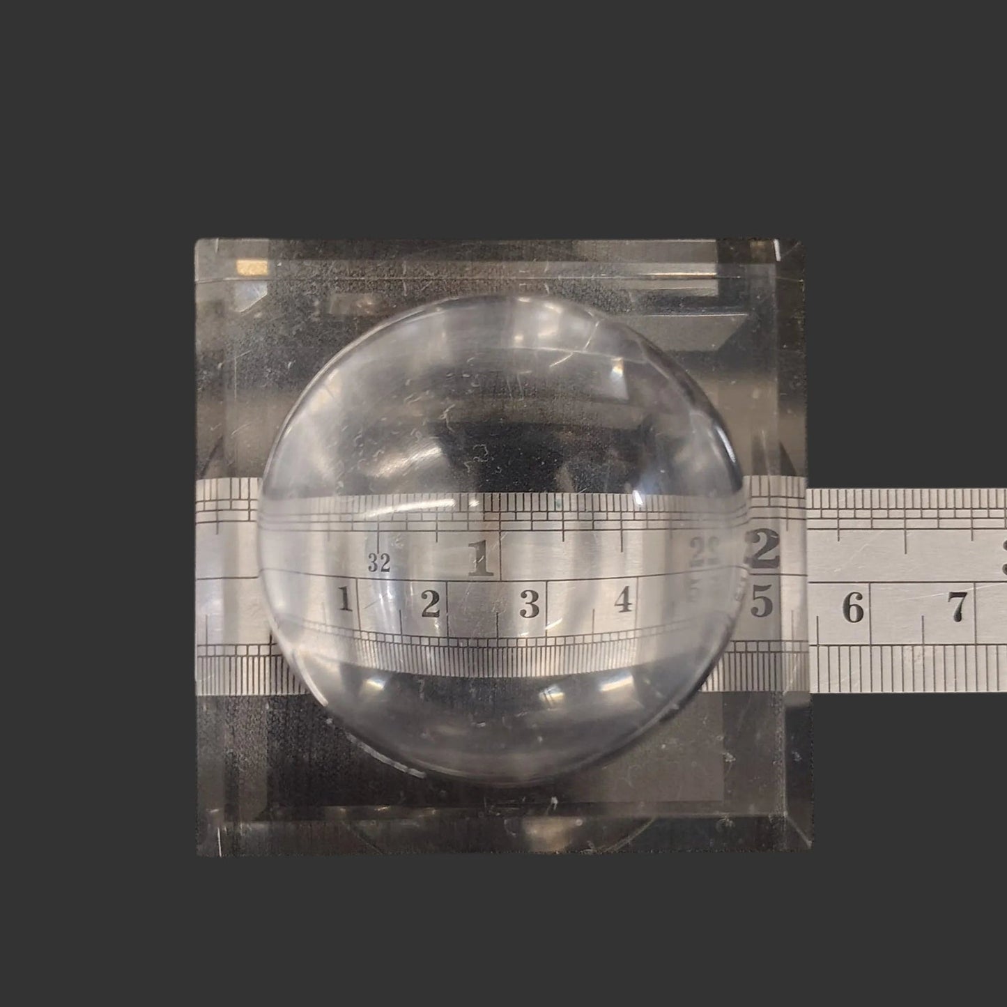 This square acrylic display stand is 2 inches in diameter.