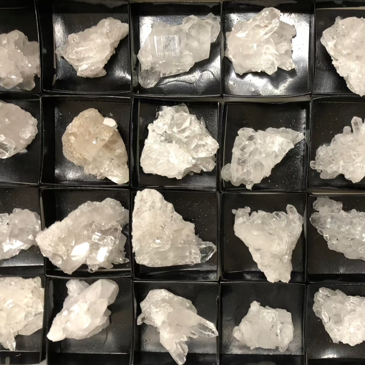 crystal clusters in a black tray inside a white box