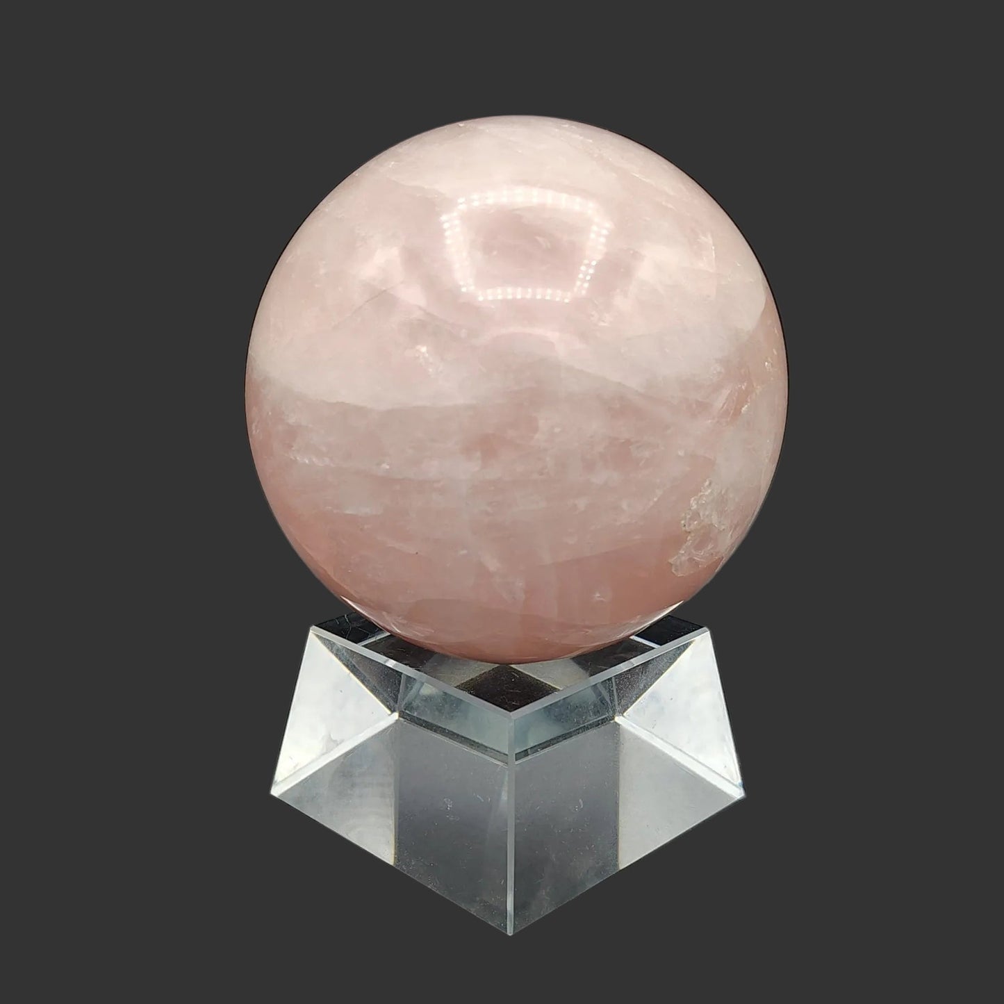 This is the right side of this polished pink rose Quartz sphere on a clear square stand.