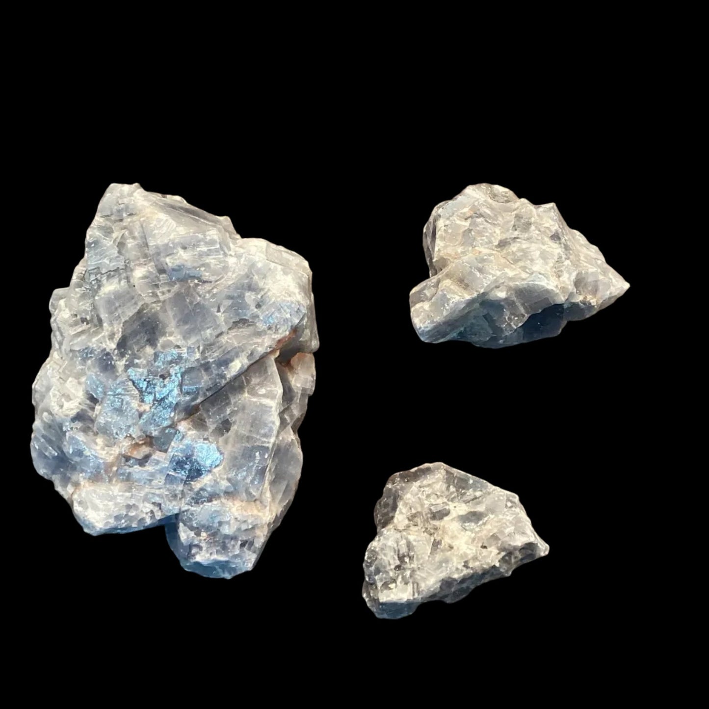 Three rough blue crystals on a brown surface