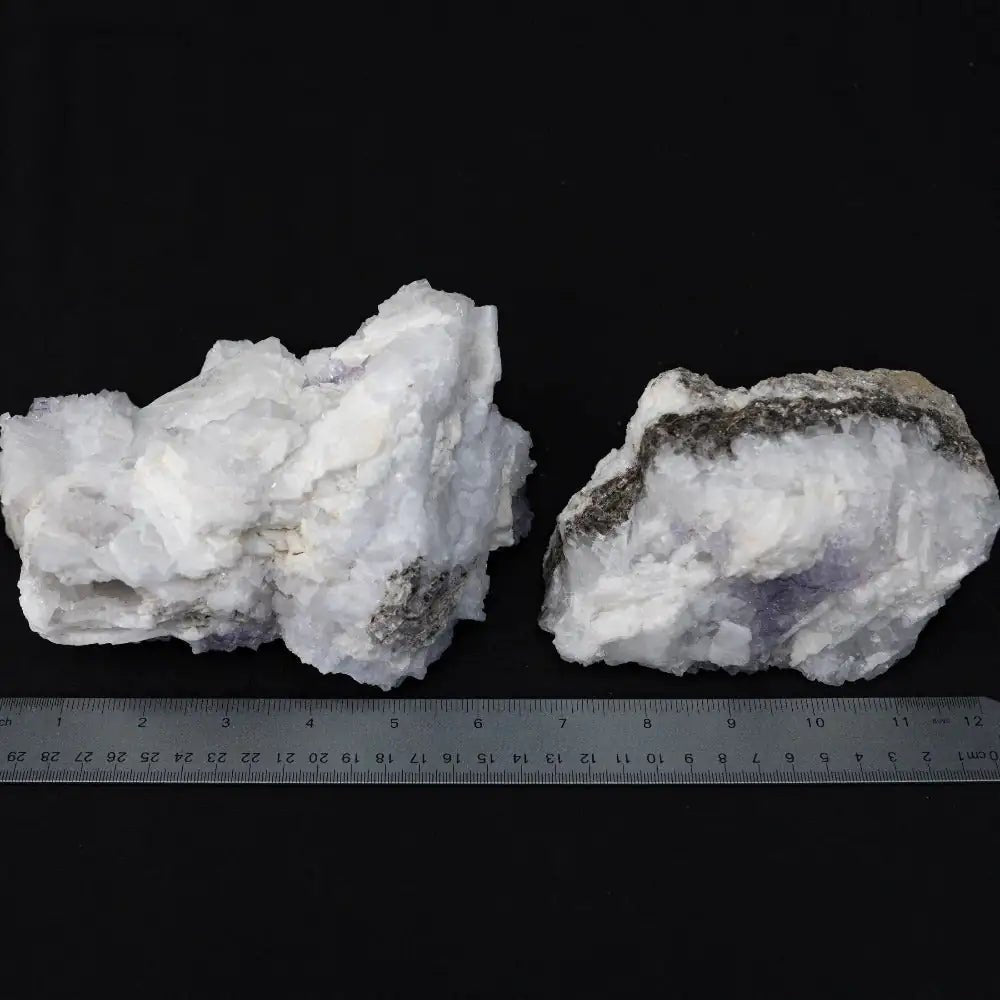 Tow white and purple rocks with a metal ruler in the front