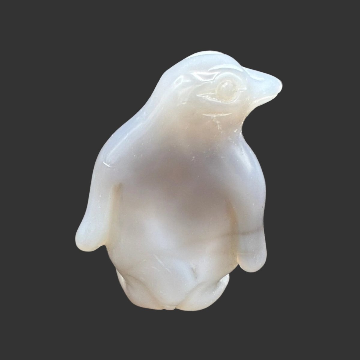 Back side of this polished Agate penguin, in front of a black background.