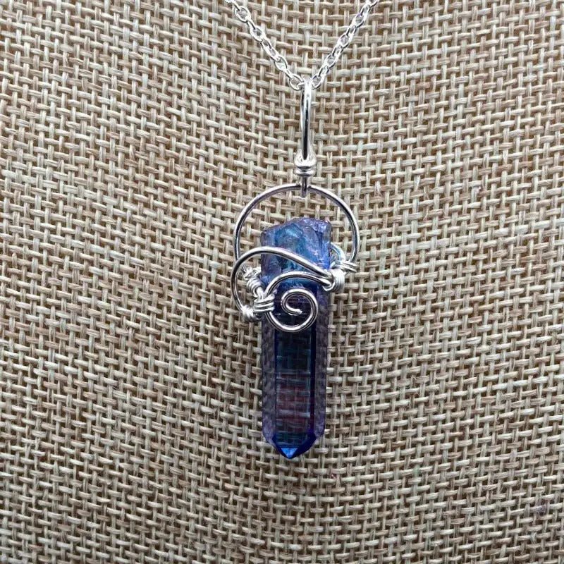 Close Up Of Aqua Aura Wire Wrapped Crystal Pendant. It Is A Bluish Purple In Color.