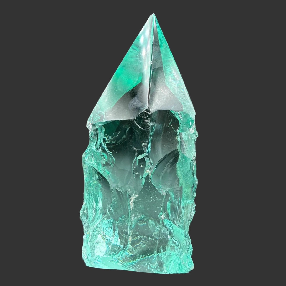 This is the right side of this blue green slag glass freeform, in front of a black background.