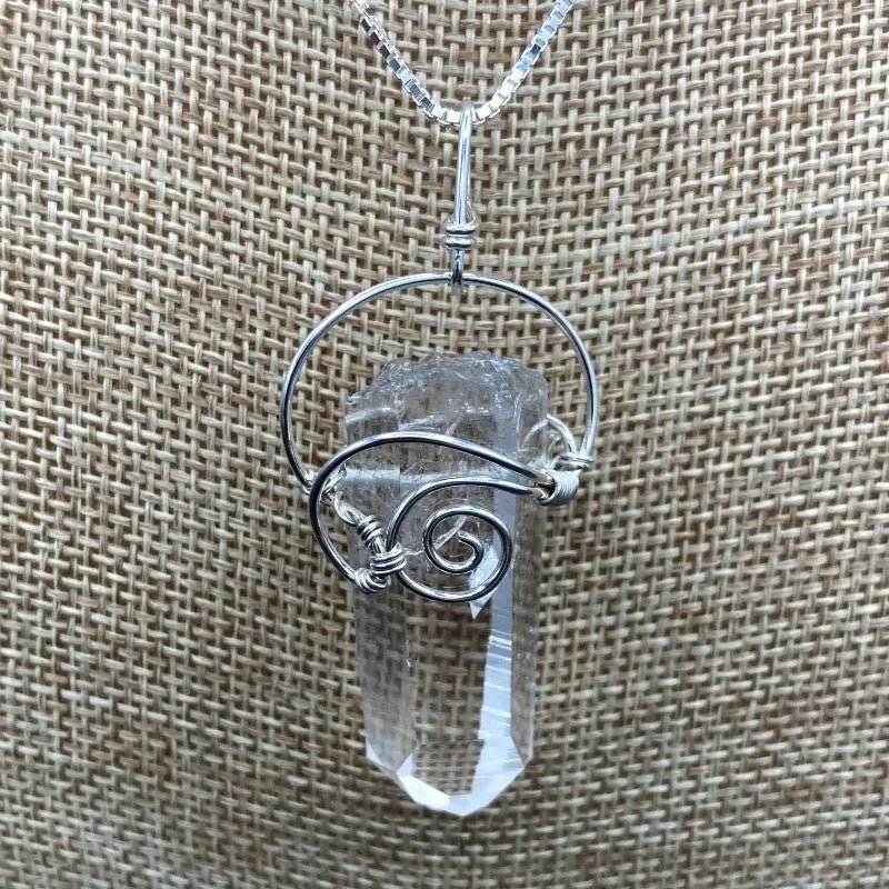 Close Up Of Crystal Pendant, Wrapped In Sterling Silver Wire In A Curly Design To Hold The Clear Crystal Point