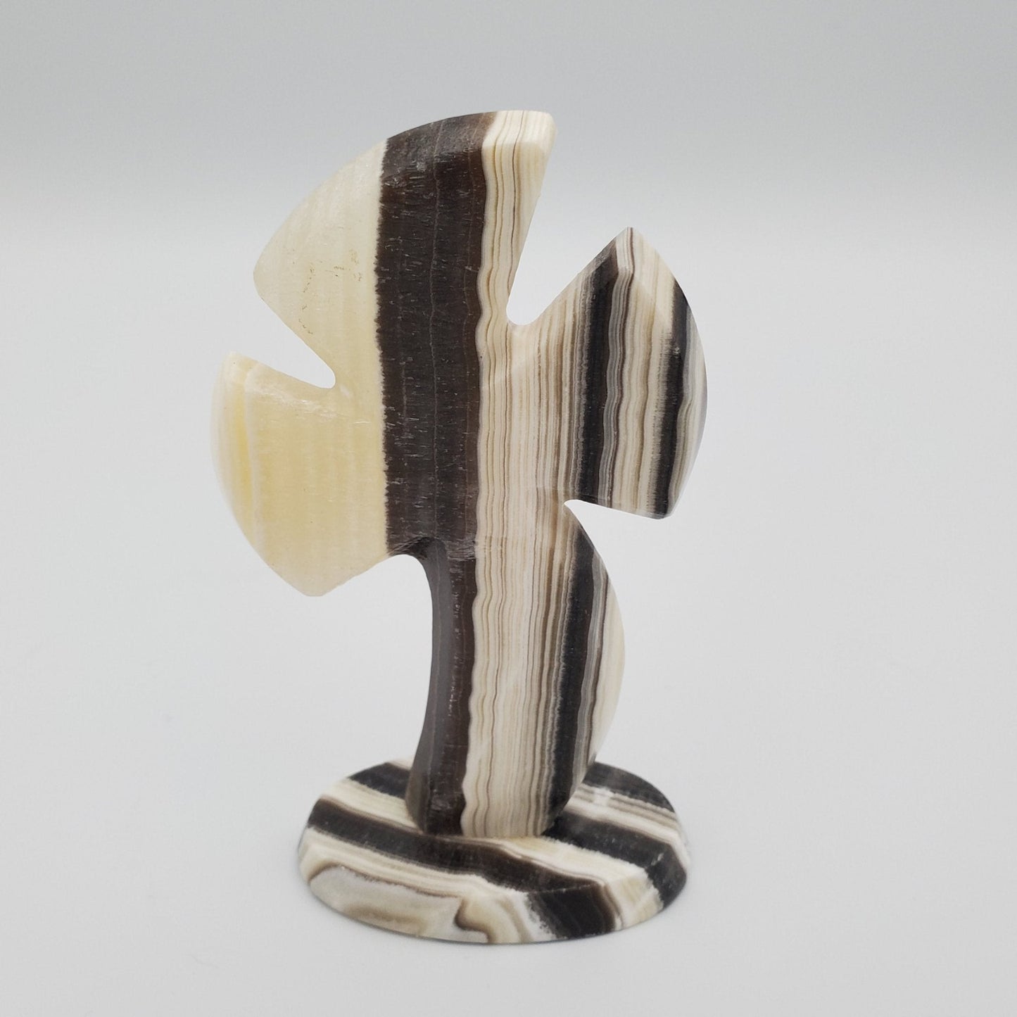 Zebra Calcite Cross alternate view displaying cream, black, white and brown natural color tones. The shape of the cross is Celtic. This view is mostly vertical striping
