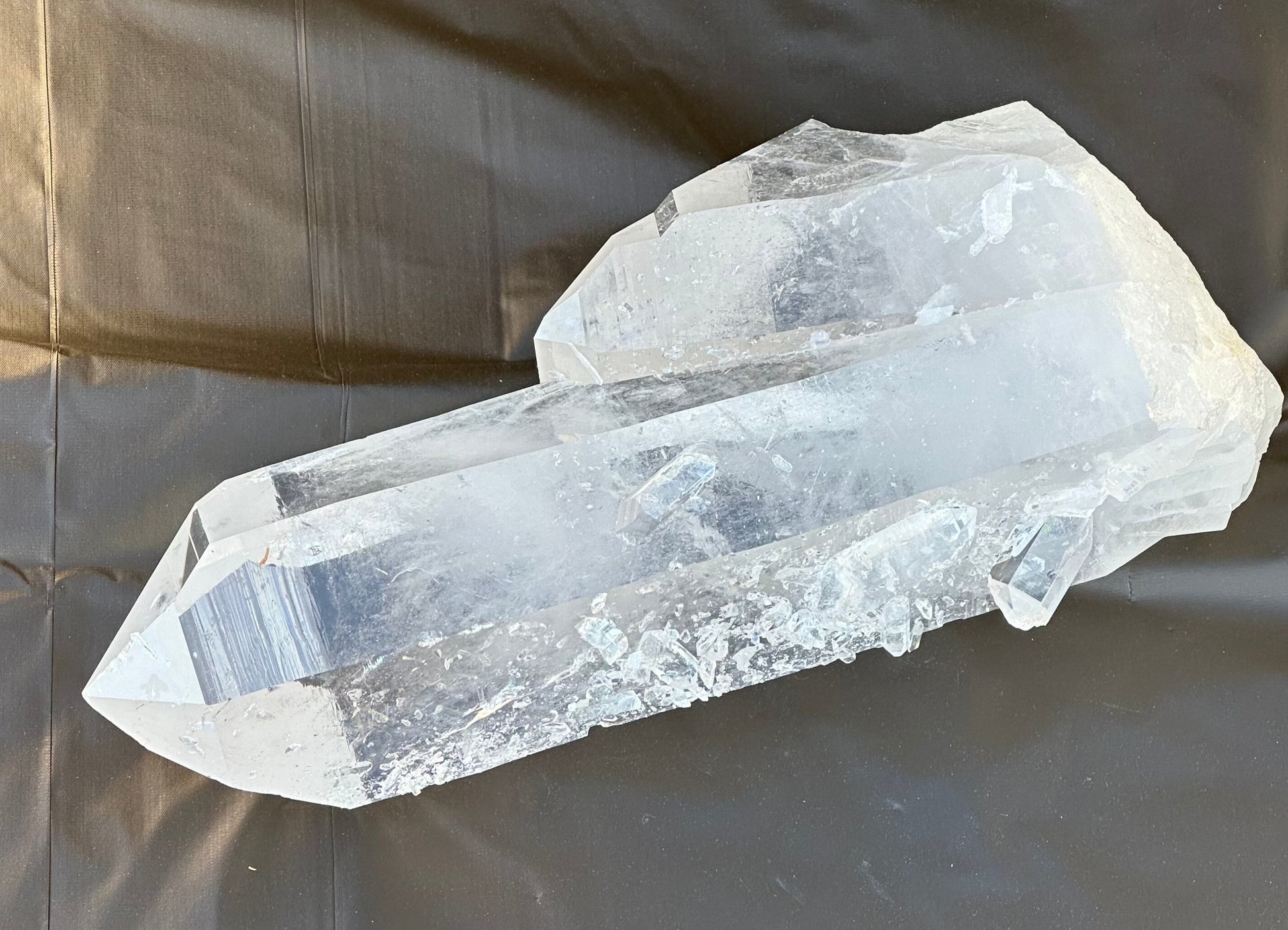 Outdoor close up image of a clear quartz crystal point with a tabular crystal growth