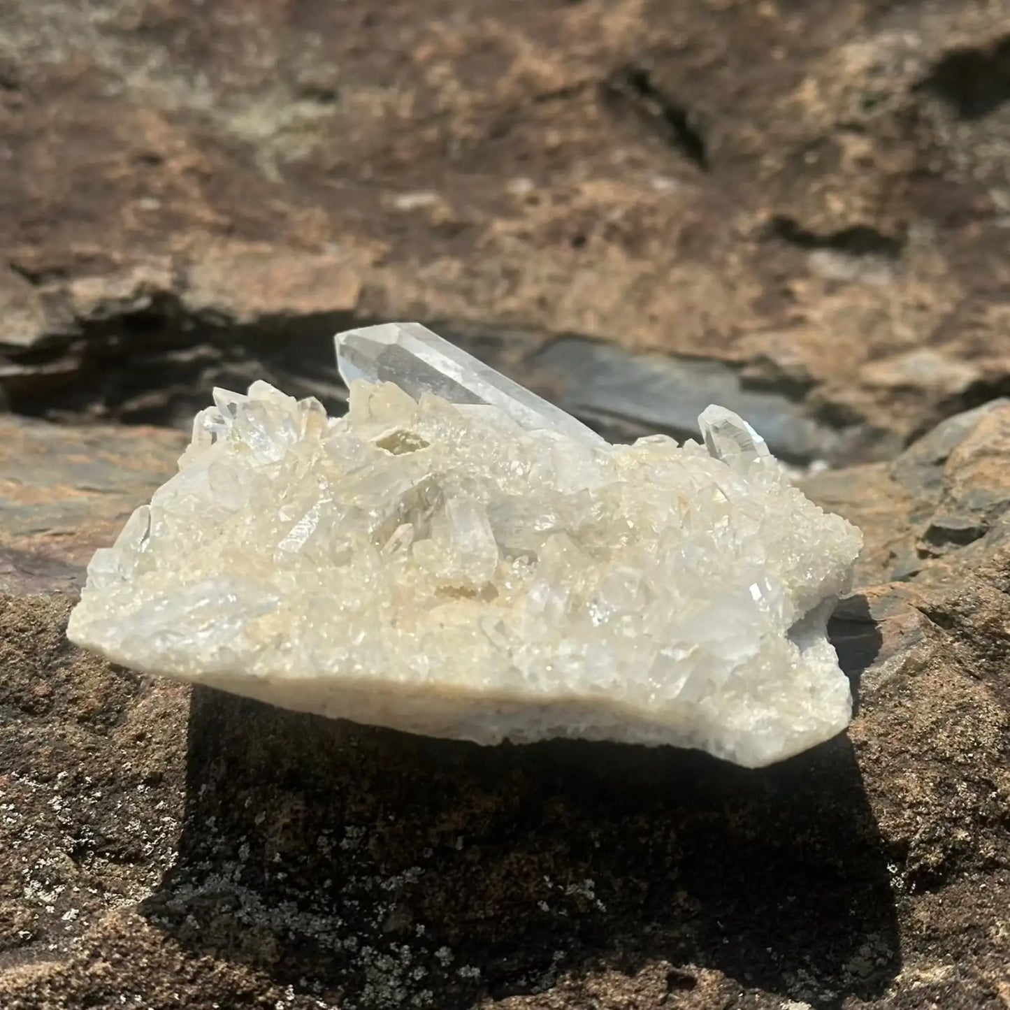 Clear and white crystal cluster with large point on a boulder