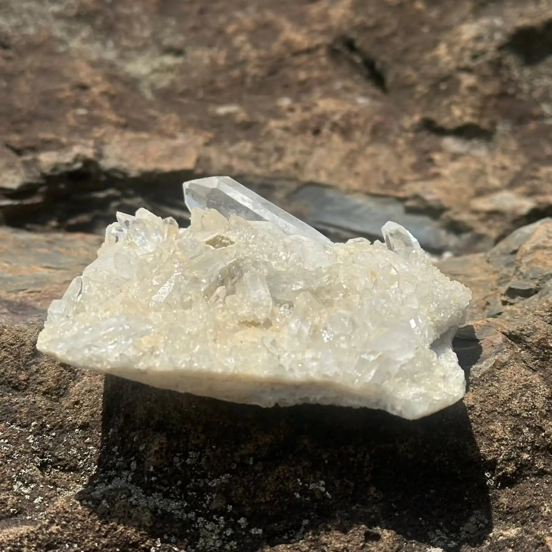 Clear and white crystal cluster with large point on a boulder