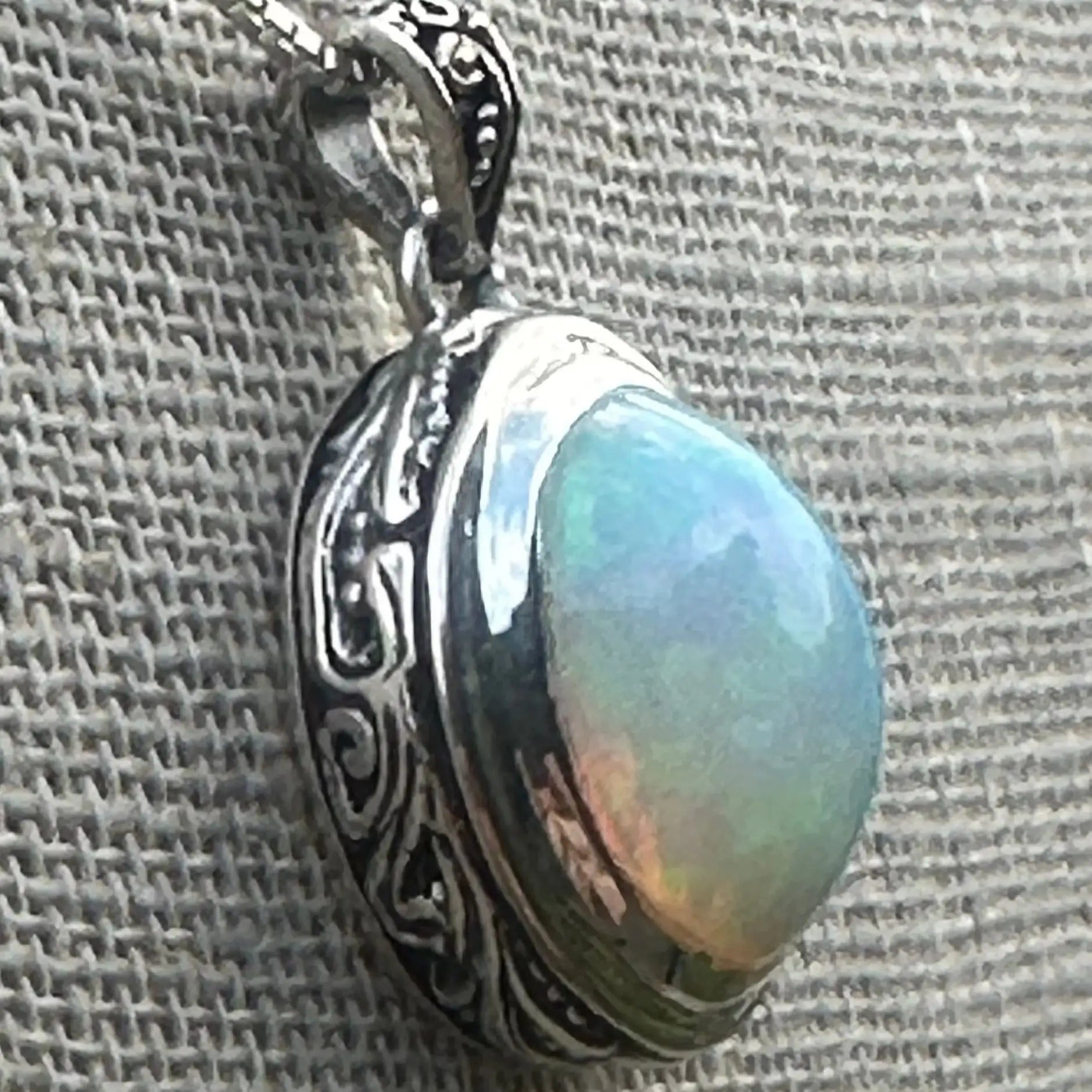 side view of sterling silver scroll design bezel holding the green tone opal