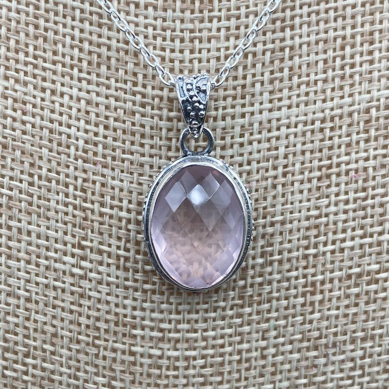 Close Up Of Rose Quartz Pendant, It Is Light Pink In Color And Oval In Shape