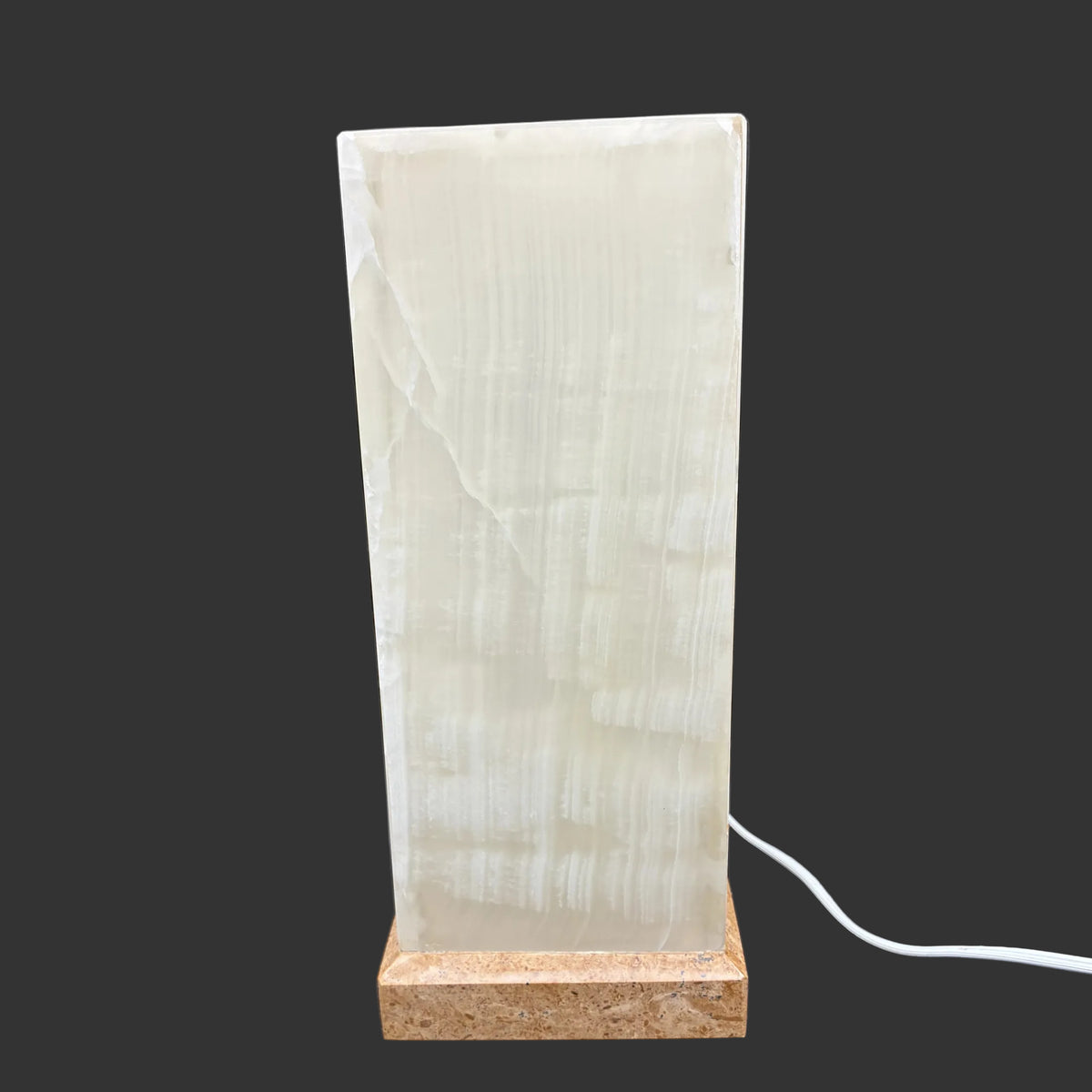 View of this lamp with the light turned on, and in front of a black background.