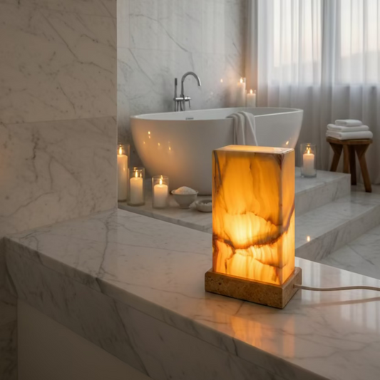 front side of this polished banded onyx table lamp, with the light turned on and in a master bathroom.