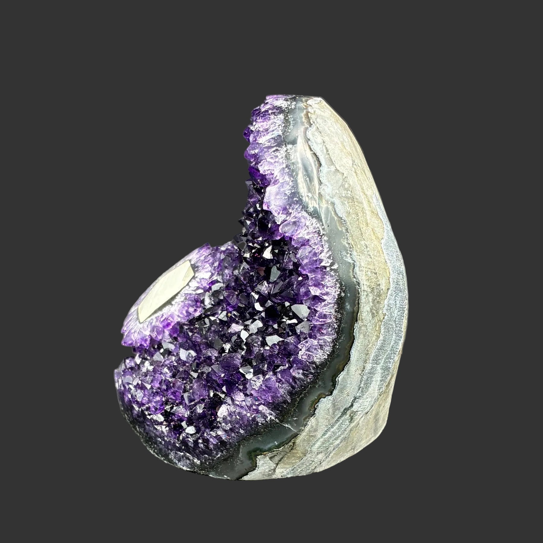 This is the left side of this dark purple Amethyst drusy cluster, and in front of a black background.