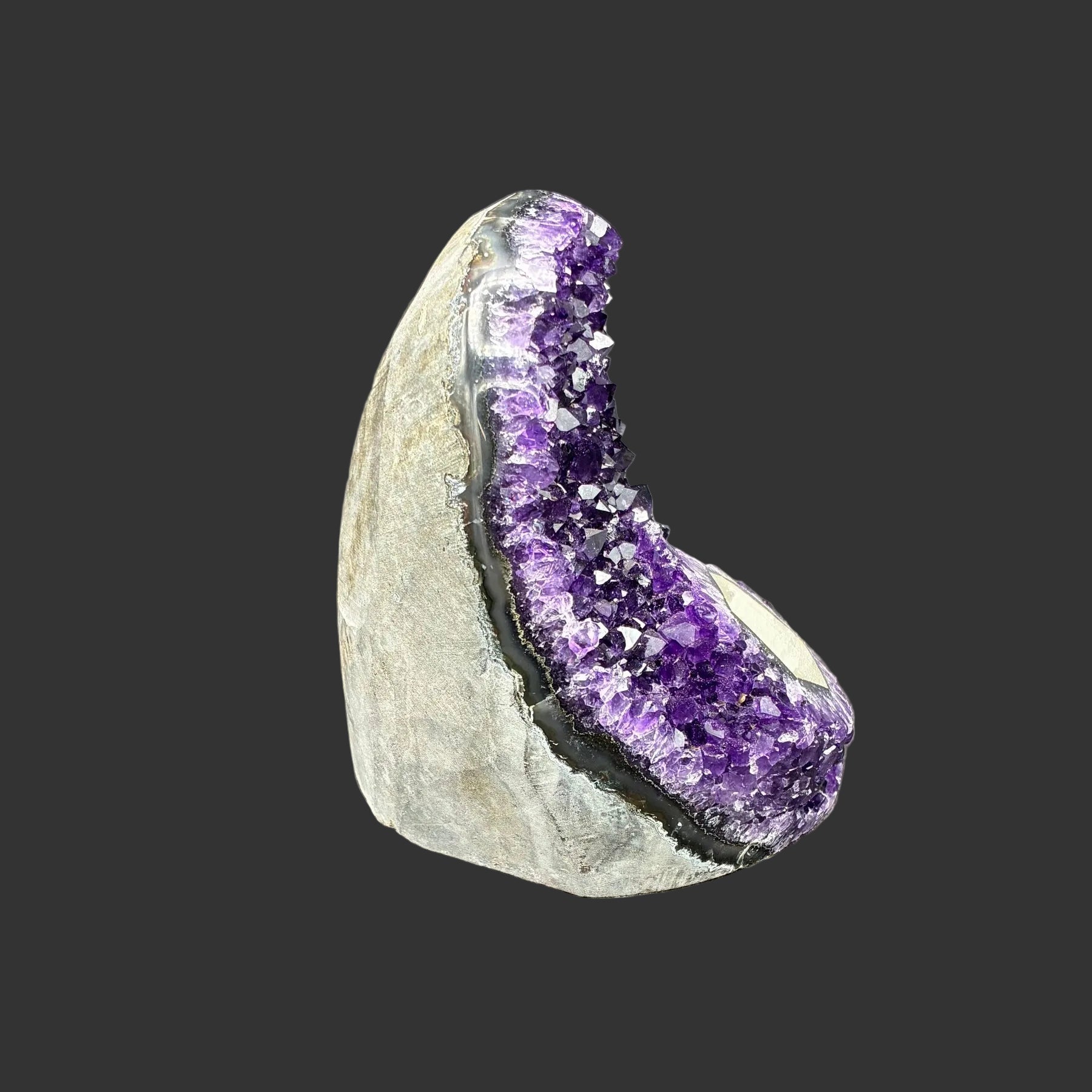 This is the right side of this dark purple Amethyst drusy cluster, and in front of a black background.