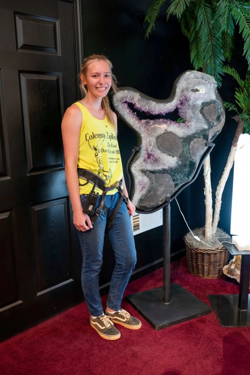 Amethyst Geode Slice Carved Stone 360 Rotating Black Stand with female standing beside it.