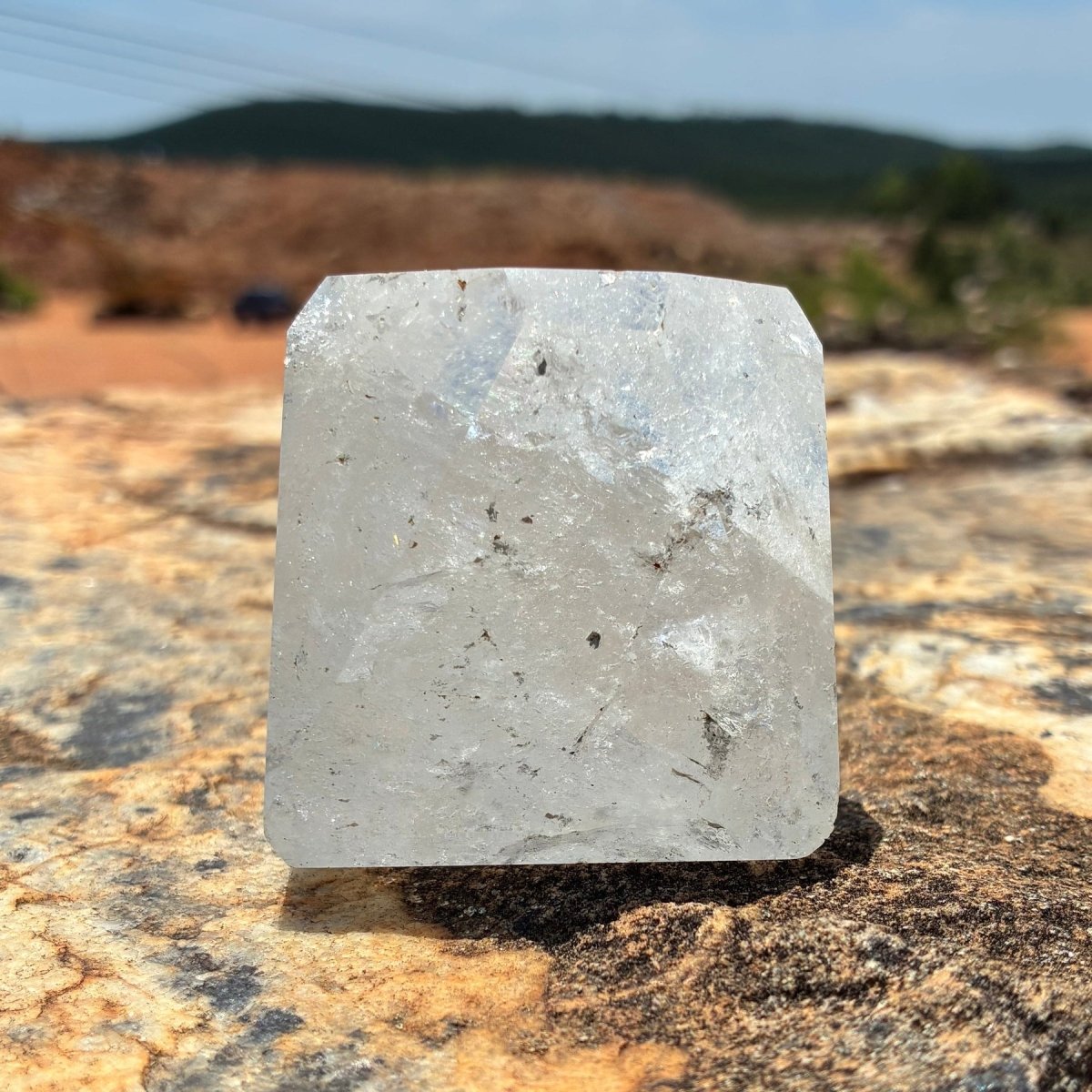 Back side of this polished and cut clear Brazilian quartz piece, on a boulder and outdoors.