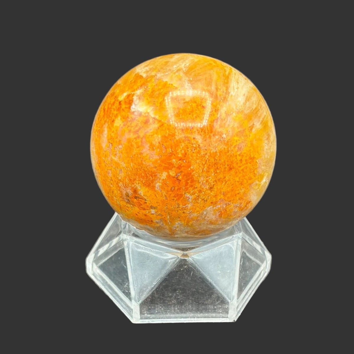 Left side of this polished Bumblebee Jasper sphere on a clear acrylic stand, in front of a black background.