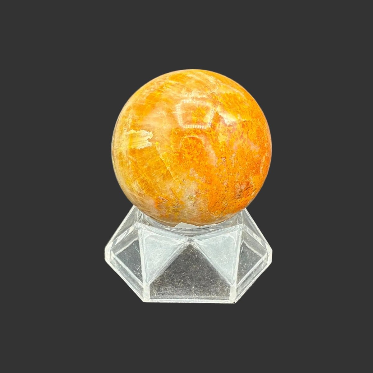 Front of this polished Bumblebee Jasper sphere on a clear acrylic stand, in front of a black background.