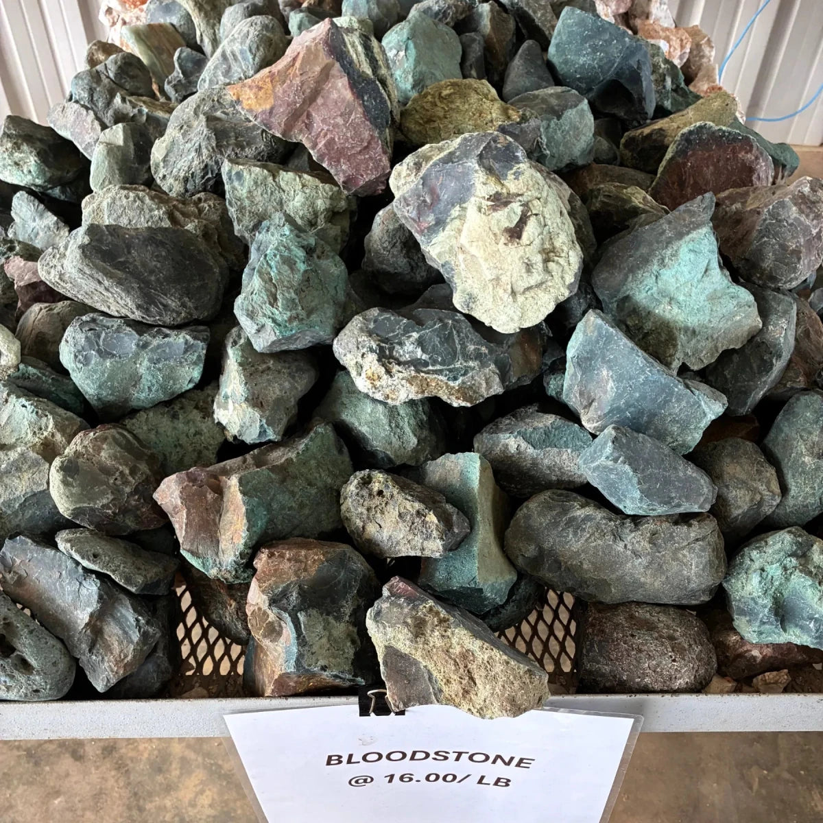 Bulk view of raw green bloodstone on a metal table outdoors.
