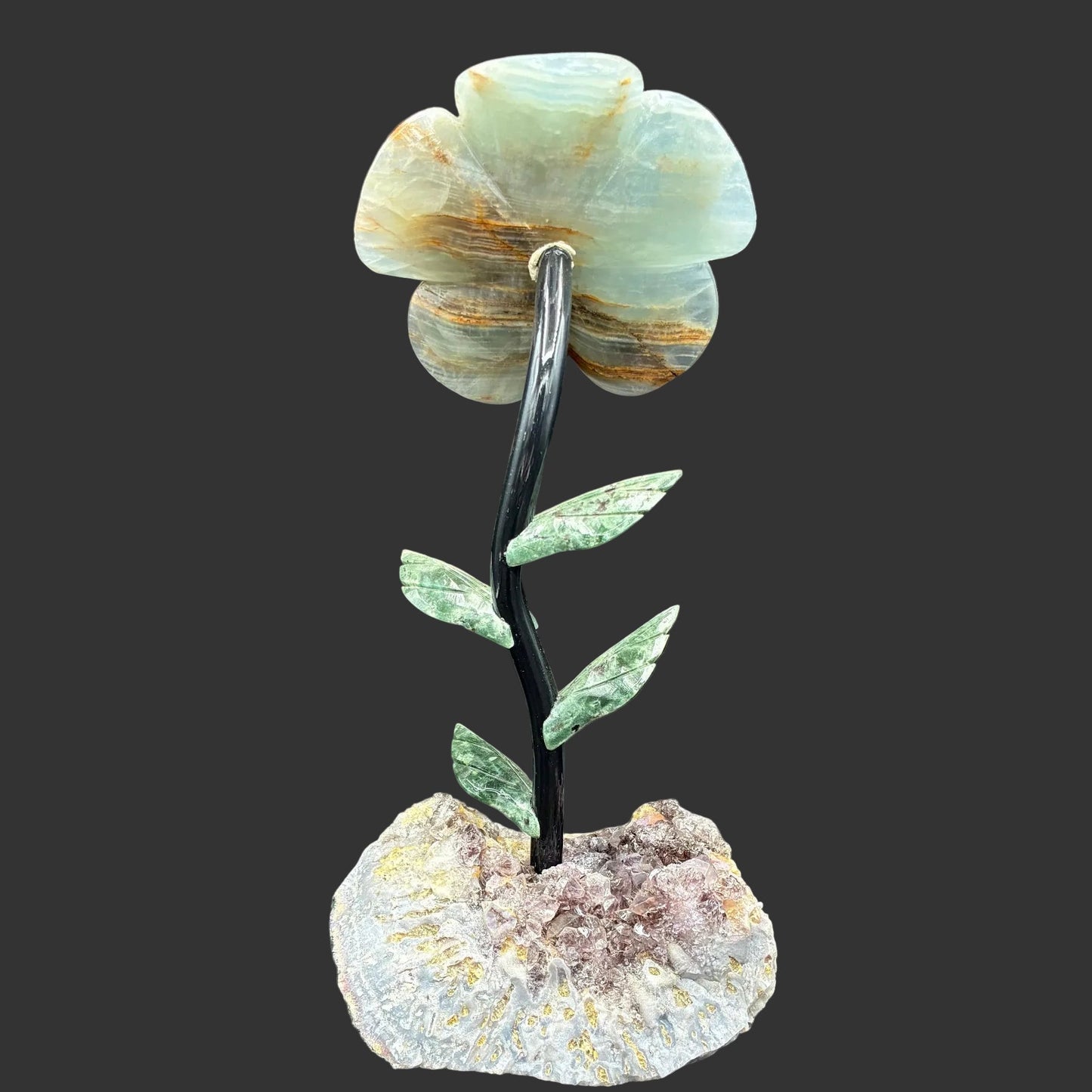 This is the back side of this blue Onyx daisy on a raw Amethyst crystal base, in front of a black background.