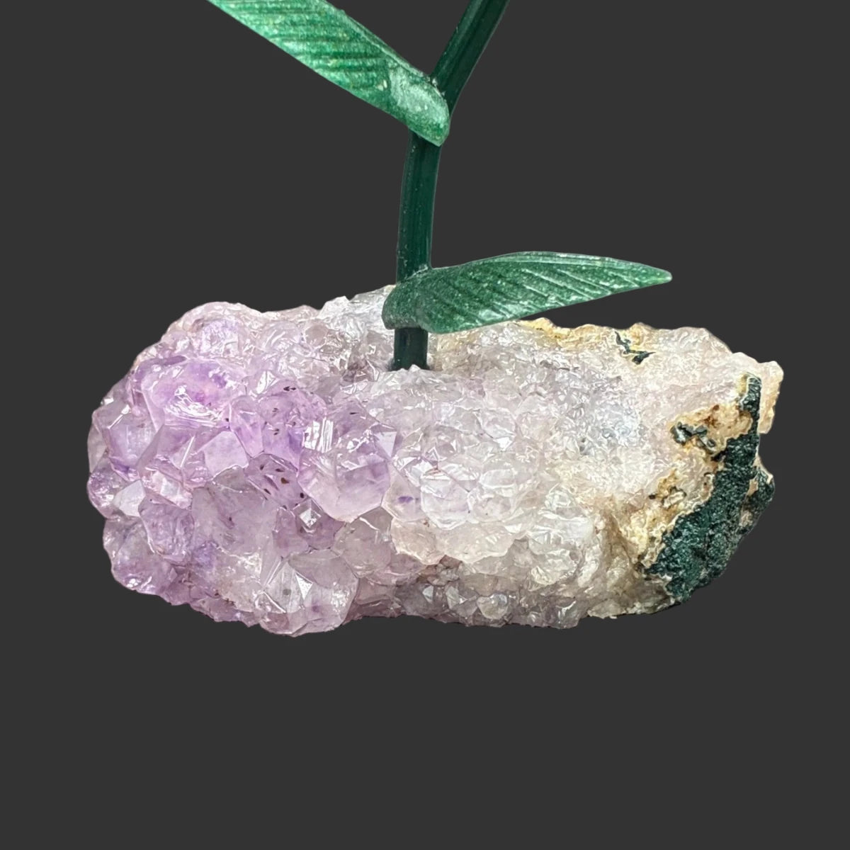 Close up of the amethyst crystal base, in front of a black background.
