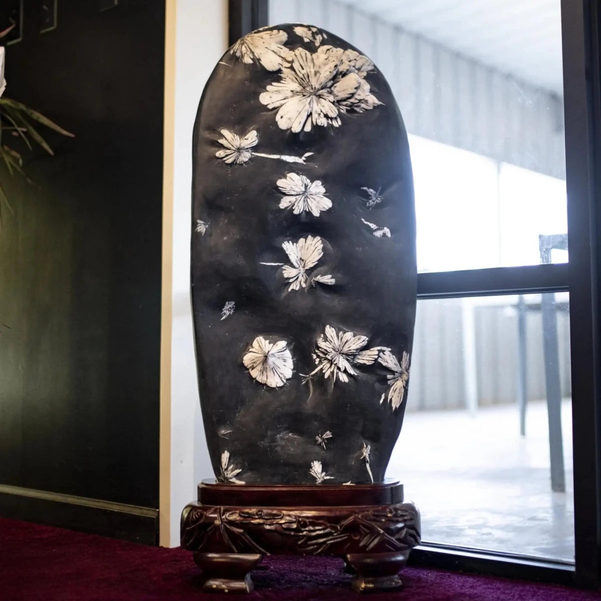 Chrysanthemum Stone On An Ornate Wood Base In Front Of A Window