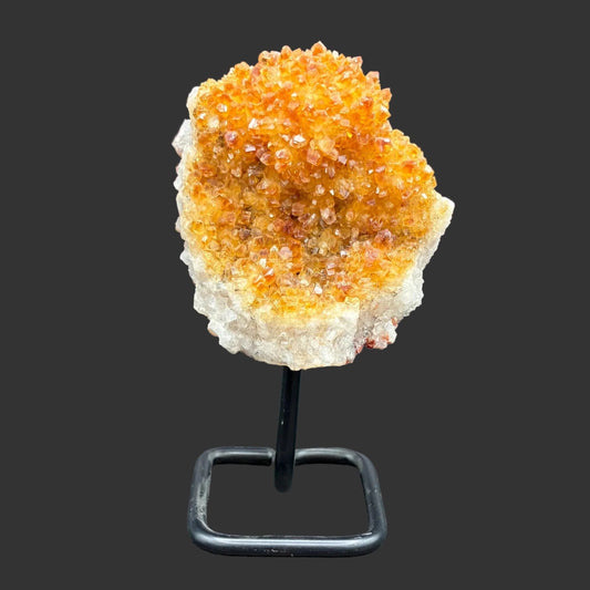 Front side of this citrine on stand, in front of a black background.