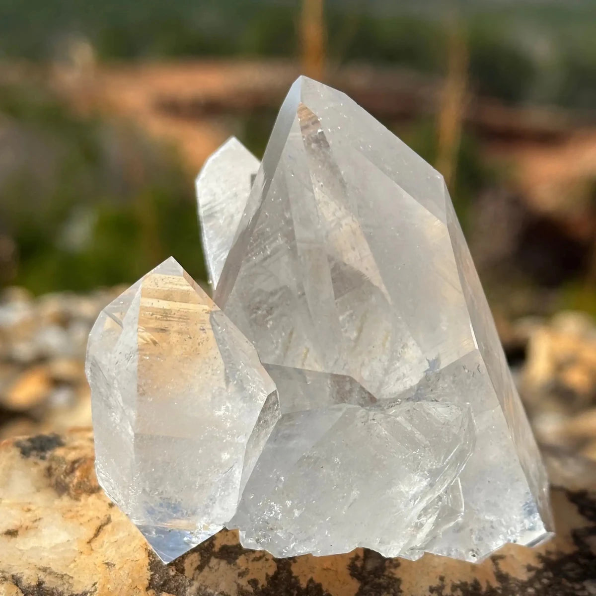 Smaller Thick Crystal Points On A Large Point within a cluster of crystals with trees and dirt road in background