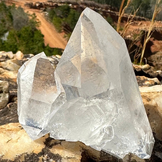 Close Up of Tabular crystal On A Cluster of Crystals Sitting on a rock overlooking a dirt road and trees