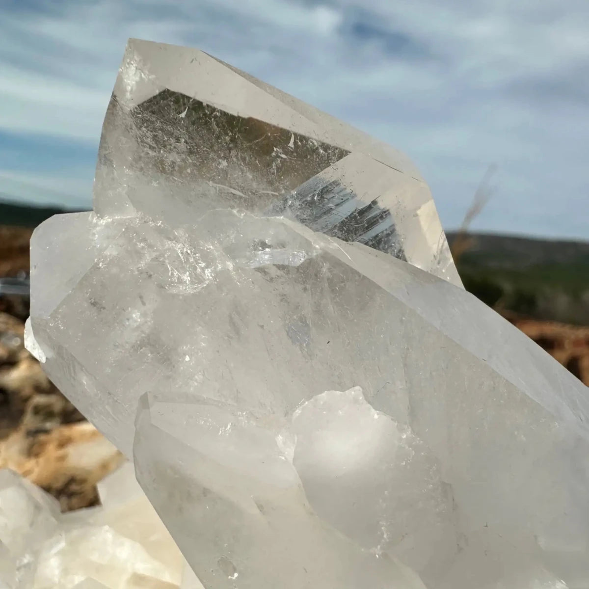 Close up of large point on a cluster of crystals sky and mountain in background