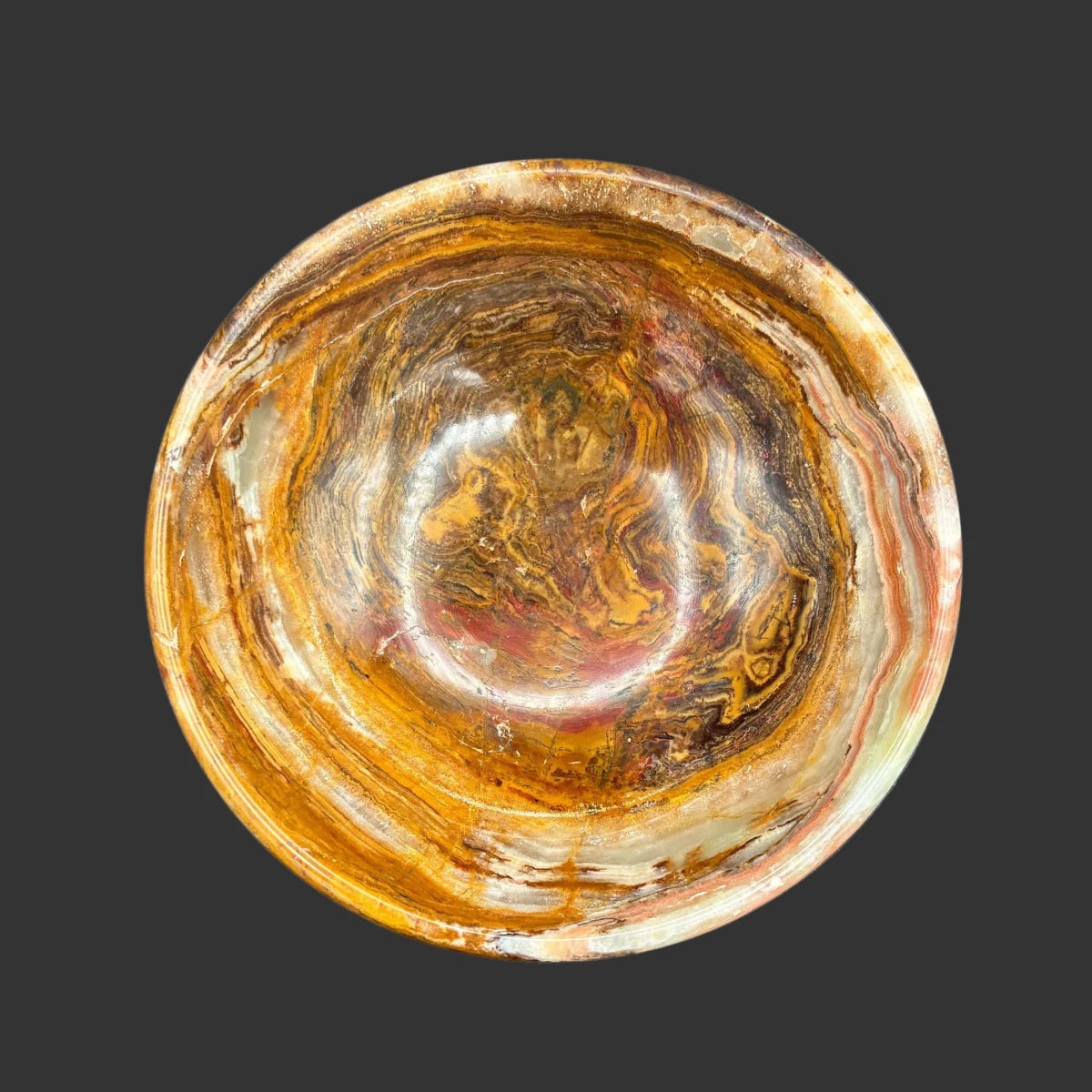 Top view of this banded onyx bowl, in front of a black background.