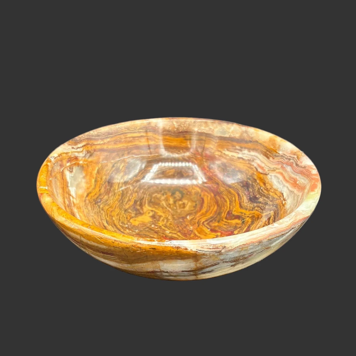 Front view of this small banded onyx bowl, in front of a black background.