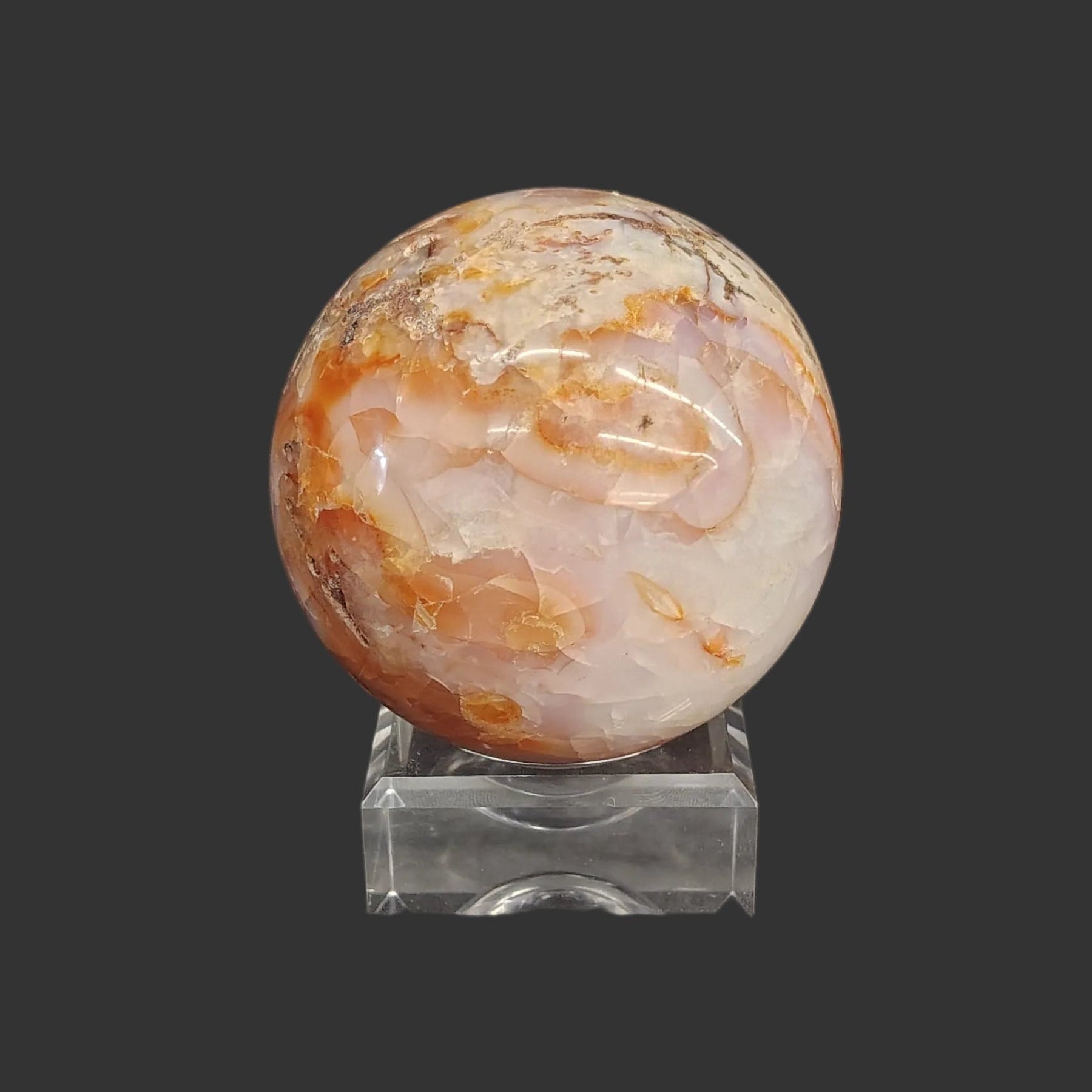 This carnelian sphere is displayed beautifully on this square acrylic display stand.