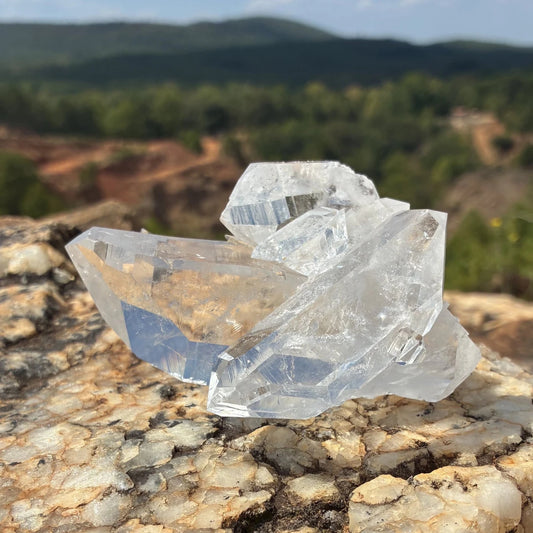 Front side of this double-terminated quartz cluster, on a boulder outdoors.