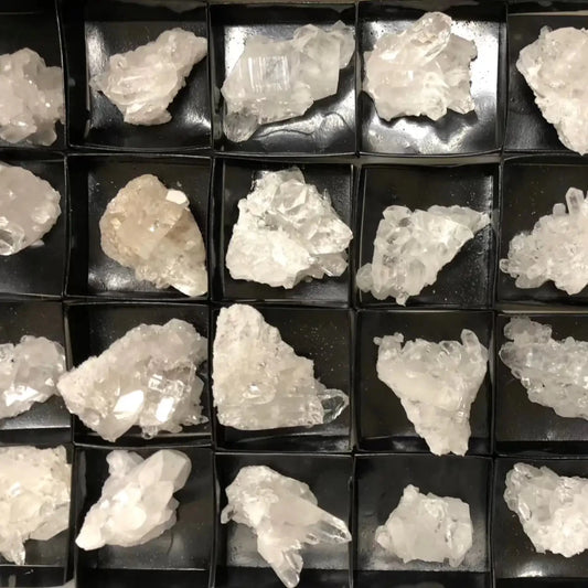 crystal clusters in a black tray inside a white box