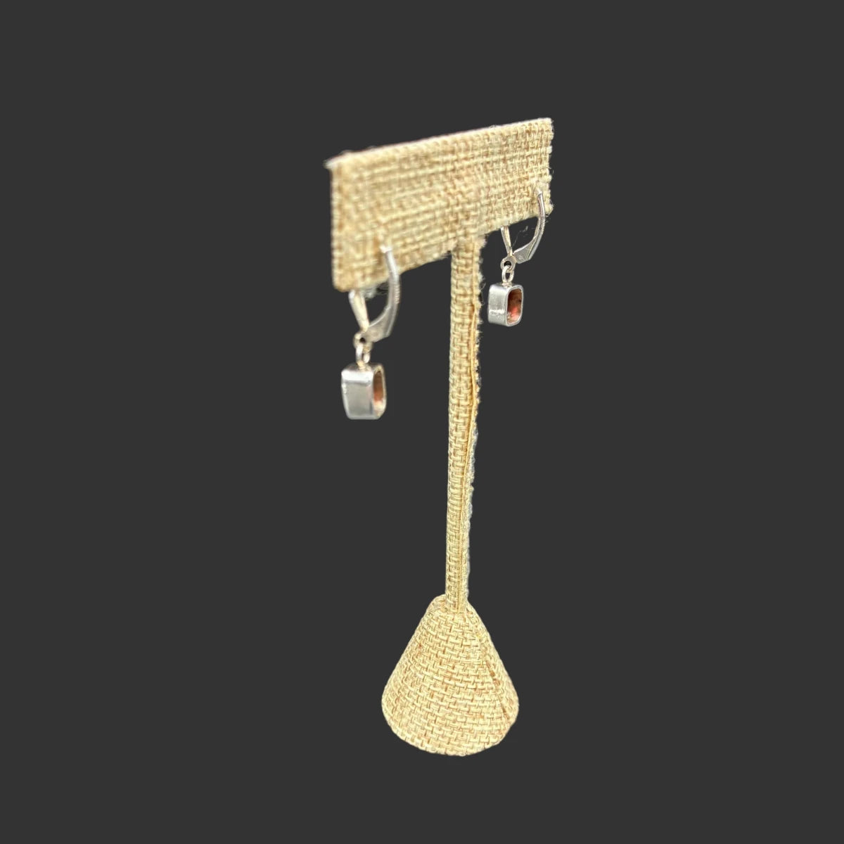 Back side of these garnet dangle earrings, in front of a black background.