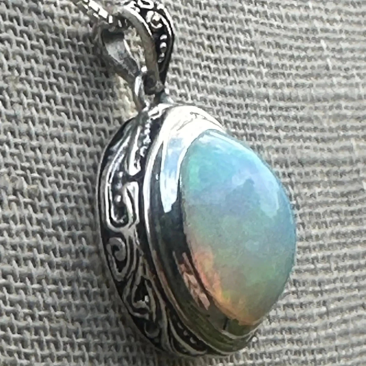 side view of sterling silver scroll design bezel holding the green tone opal