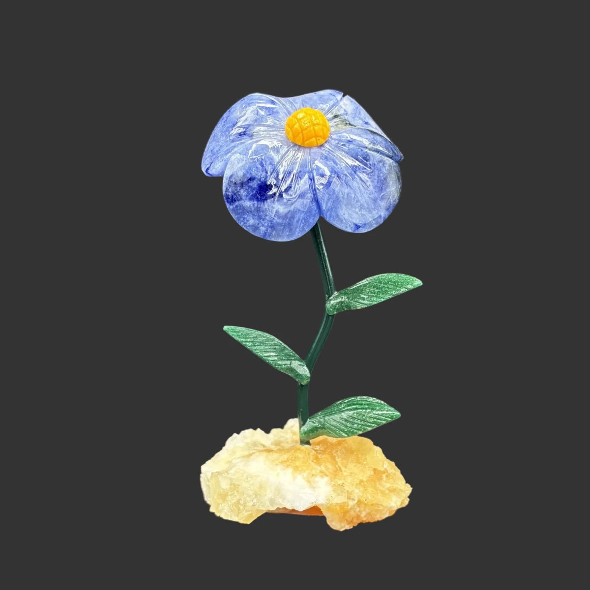 Front side of this sodalite flower with a orange calcite base, in front of a black background.