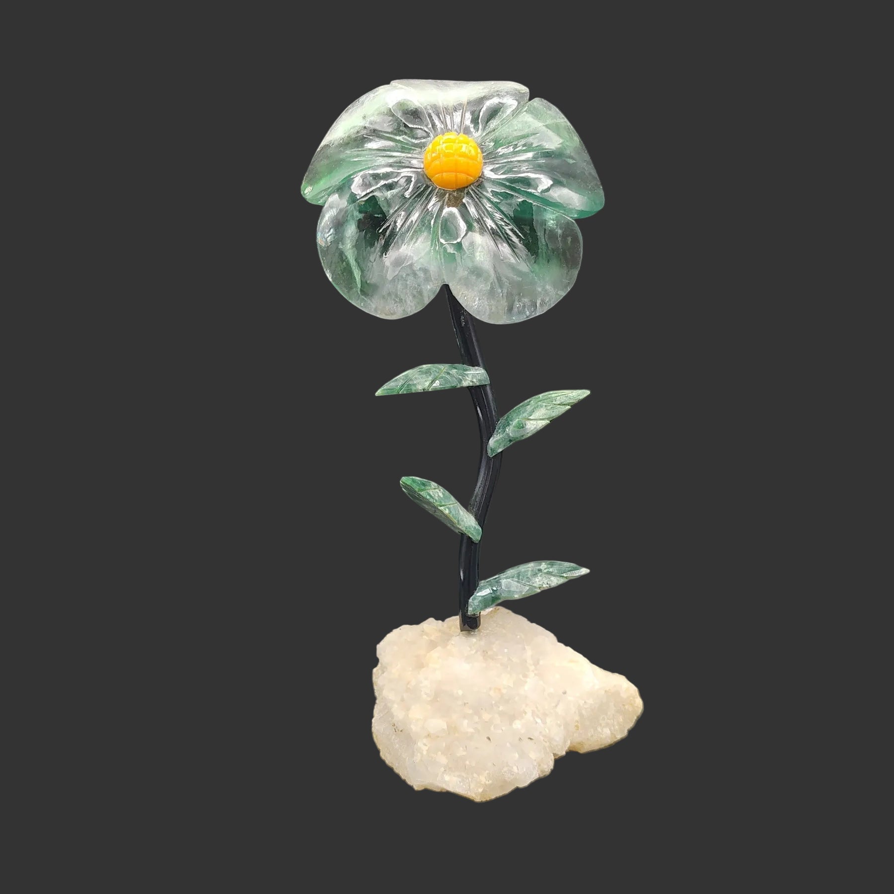 Decorative Fluorite daisy with a milky quartz base, in front of a black background.