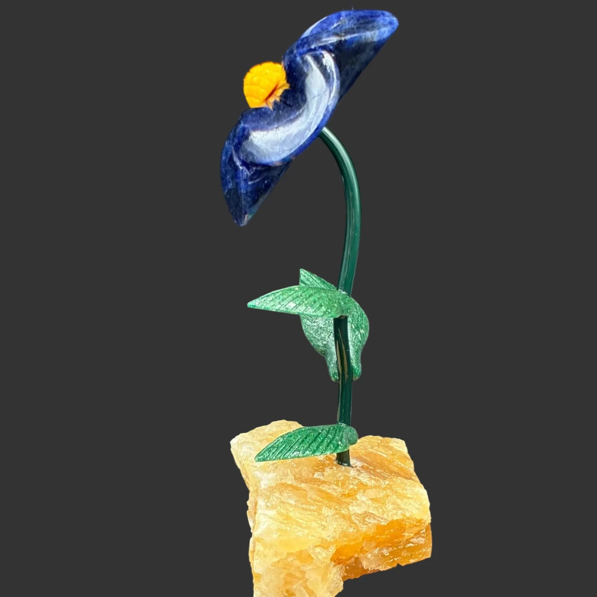 Side view of this polished Sodalite daisy, on a yellow calcite base, and in front of a black background.