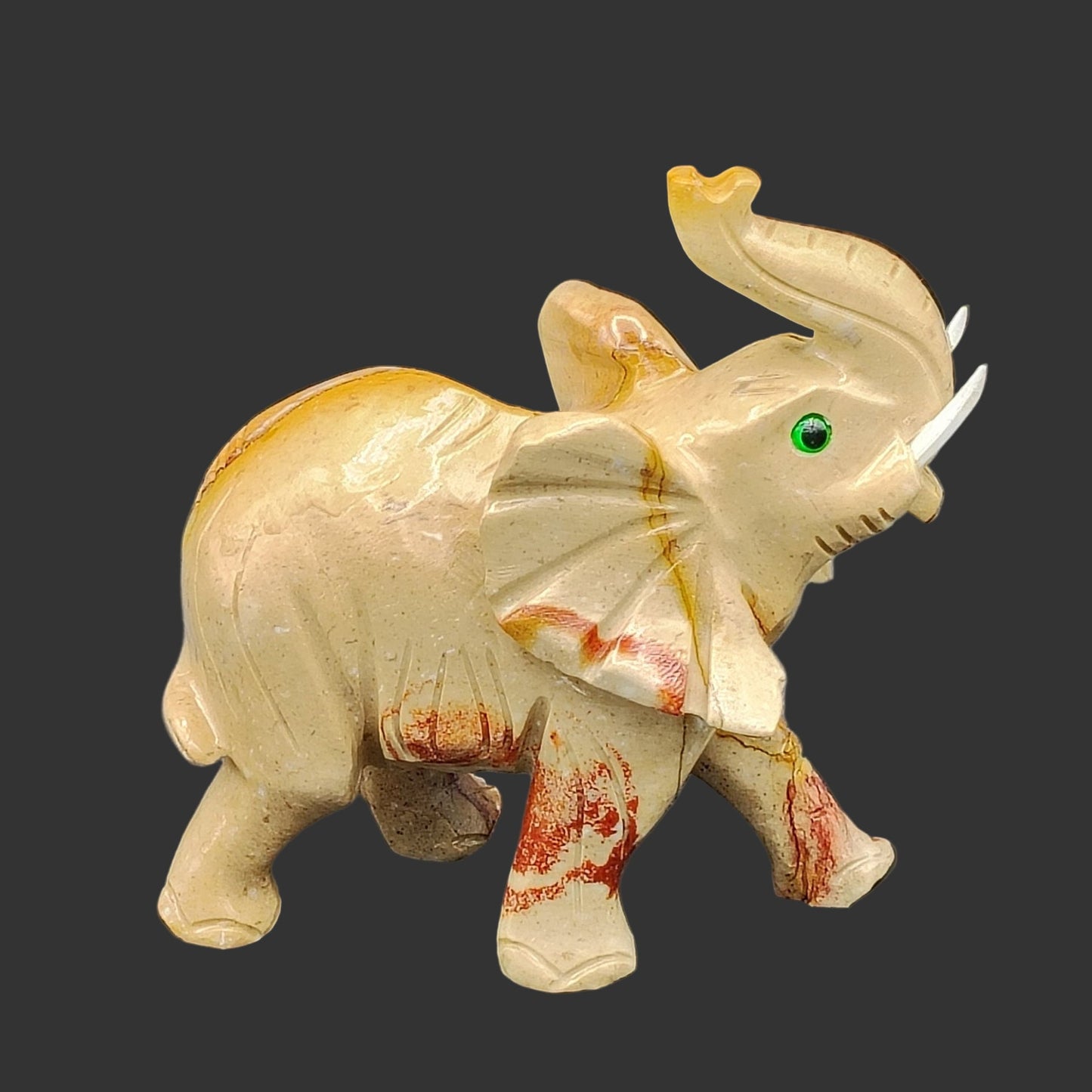 This is the right side of this hand-carved soapstone elephant, beige and brown in color, with white tusks.