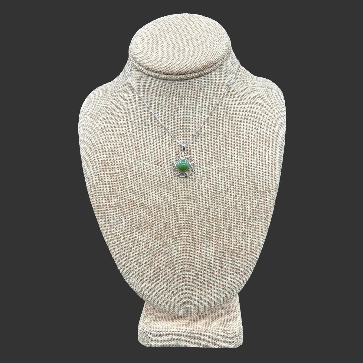 Front view of this sterling silver and jade necklace, in front of a black background.