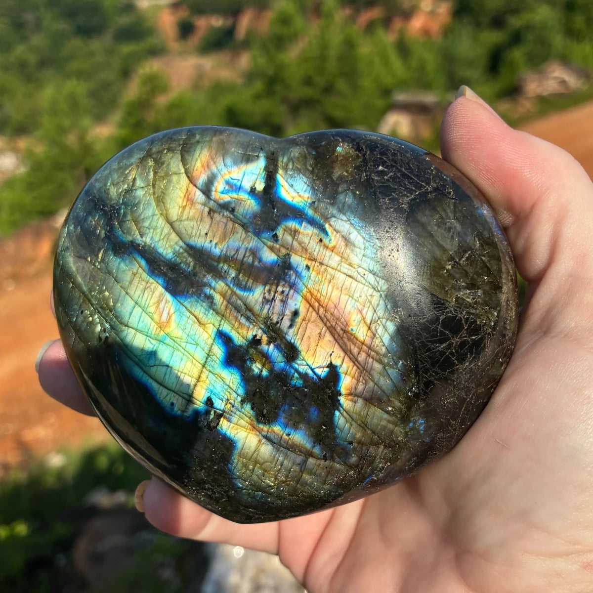 Front side of this polished Labradorite heart, in a outdoor setting.