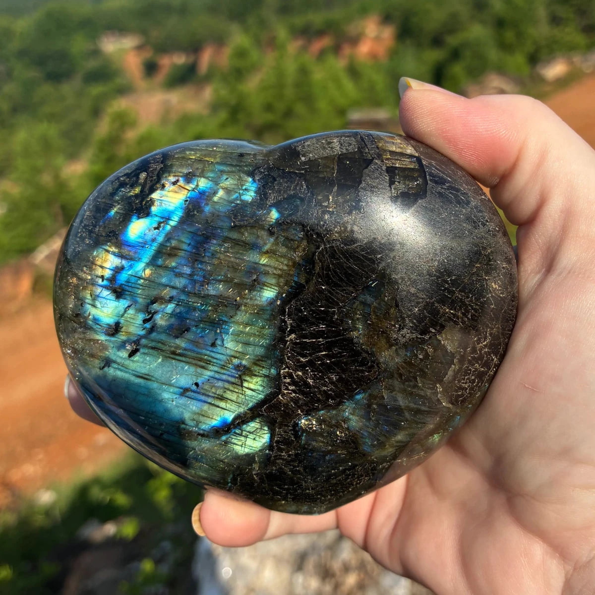 Back side of this polished Labradorite heart, in a outdoor setting.
