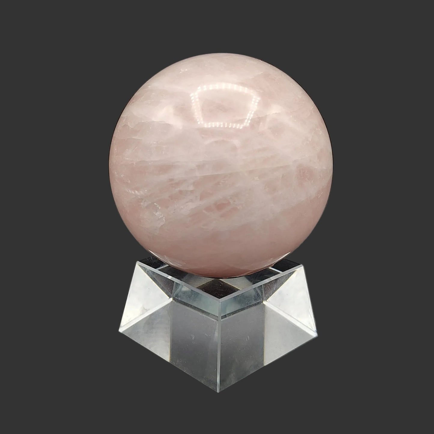 This is the left side oof this polished pink rose Quartz sphere on a clear and chunky square stand.