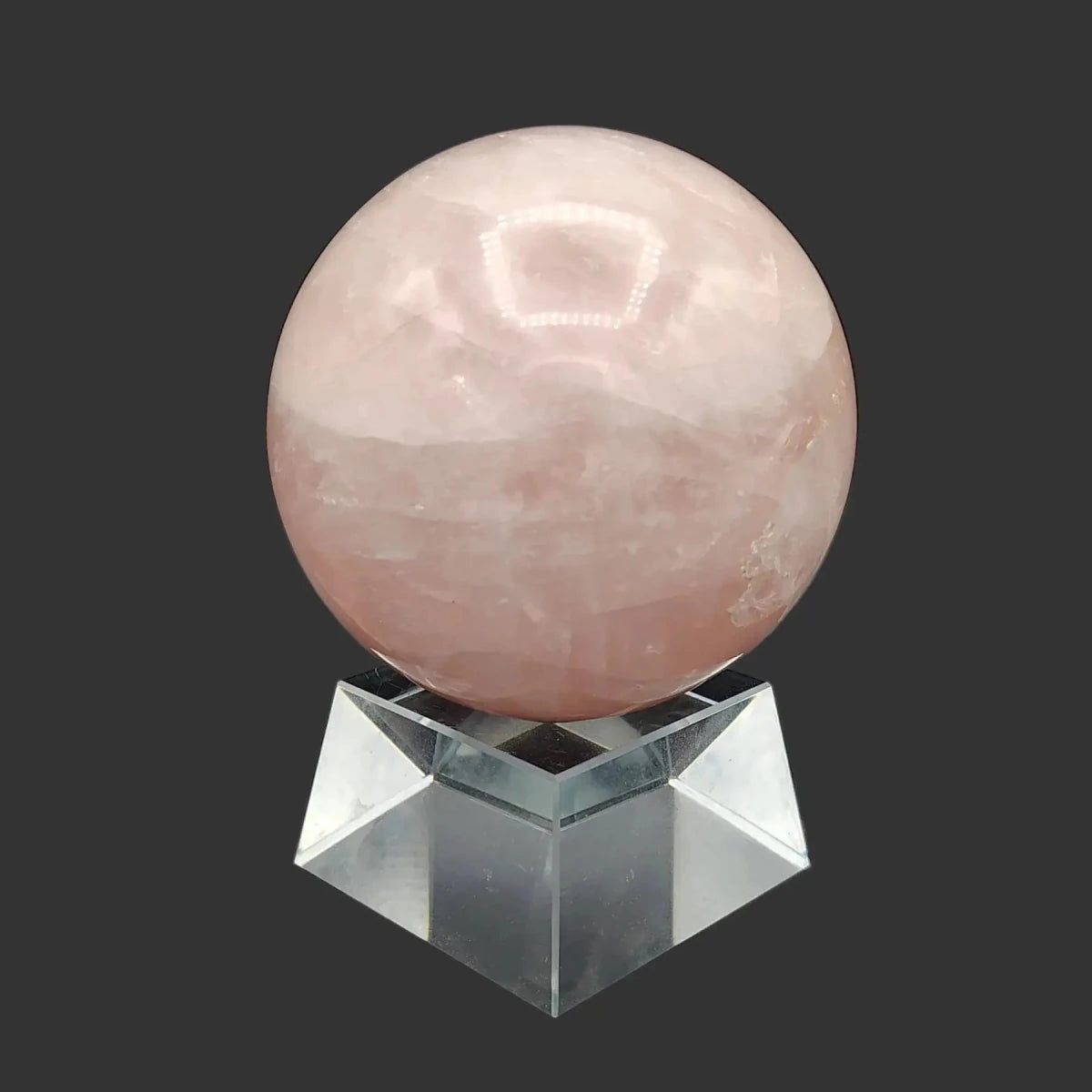 This is the right side of this polished pink rose Quartz sphere on a clear square stand.